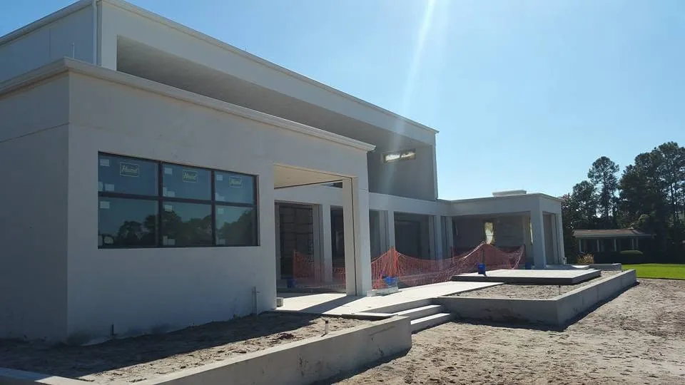 Flat roof white stucco modern home under construction sandy lot orange safety fe